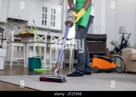 Close up of african janitor cleaning carpet with vacuum Stock Photo