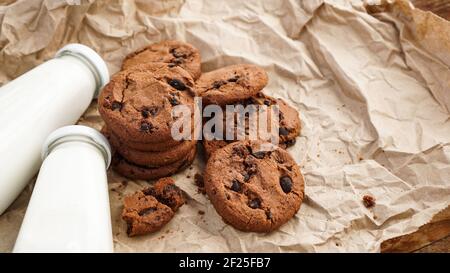 Cookies with chocolate drops on craft paper and bottles of milk Stock Photo