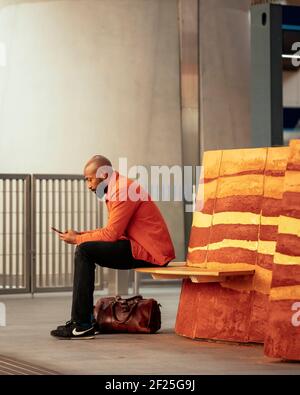 Man sitting on bench. Sitting on Londons Clay, London, United Kingdom. Architect: Local Collective, 2020. Stock Photo