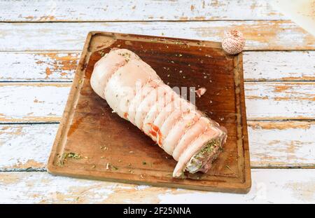 Preparation of a porchetta with a mixture of aromatic herbs placed on a piece of fresh pork belly open in the thickness Stock Photo