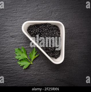 Black grainy caviar of paddlefish fish in a white ceramic bowl Stock Photo