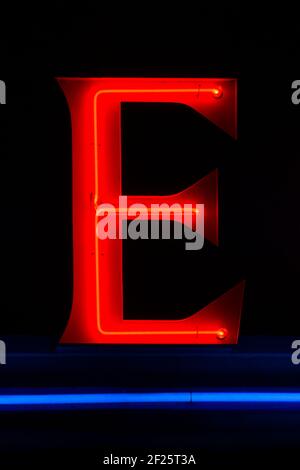 Red glowing neon letter E at night with blue underline Stock Photo