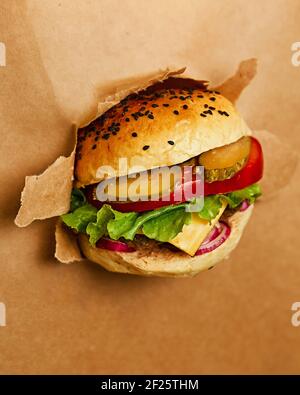 A juicy cheeseburger breaks into the craft background. Kraft paper. Promotional photo. High quality photo Stock Photo