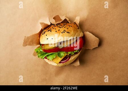 A juicy cheeseburger breaks into the craft background. Kraft paper. Promotional photo. High quality photo Stock Photo