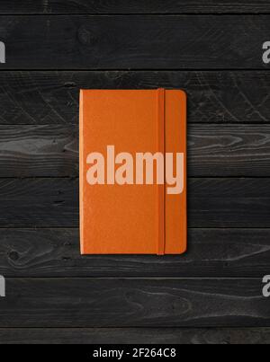 Orange closed notebook on black wood background Stock Photo