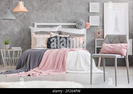 Gray chair with small pink pillow standing in a room with king-size bed Stock Photo