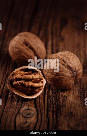 Three ripe walnuts on textured wood brown background. Closeup. Selective focus Stock Photo