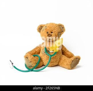 Cute brown teddy bear with a patch, a silk yellow ribbon in the shape of a loop Stock Photo