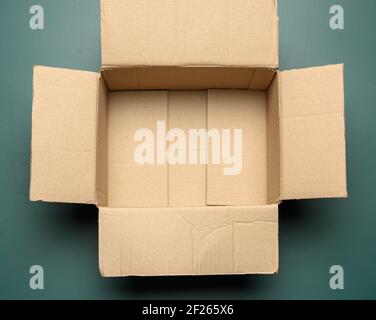 Open empty cardboard rectangular box made of corrugated brown paper on a green background Stock Photo