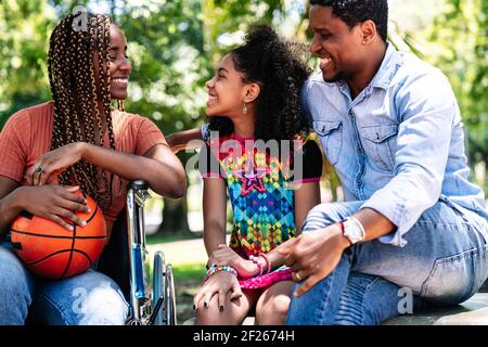 Woman in a wheelchair at the park with family. Stock Photo