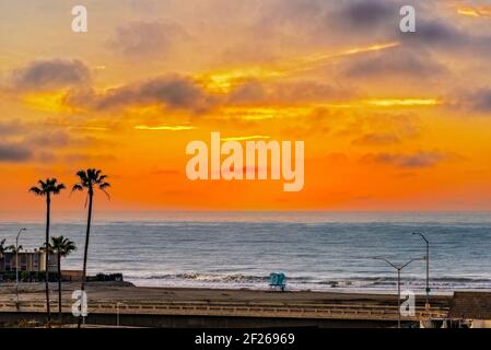 Sunset skies over bridge and beach with ocean beyond. Stock Photo