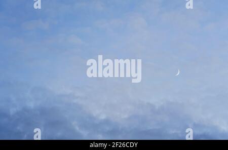 Evening sky with some barely visible clouds, moon crescent in right side - blue hour background Stock Photo