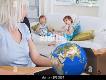 Composition of cardboard box with globe and mother with two daughters using tablet Stock Photo