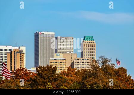 11-7-2020 Tulsa USA Skyline of Tulsa OK - wit modern and Art Deco buildings - viewed over fall trees with American flags waving in foreground Stock Photo