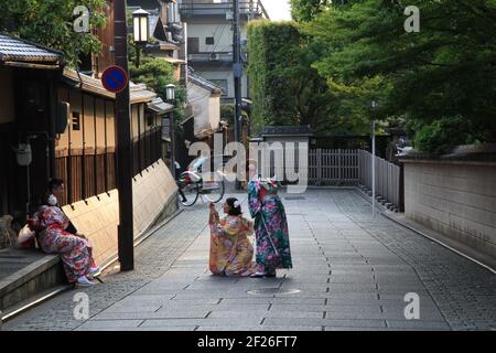 In the Gion District of Kyoto, Japan, a young couple giggle and pose for photos in traditional Japanese Kimonos while their friends take the photo Stock Photo