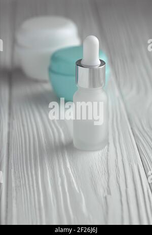 Pipet bottle and cream containers on wooden table Stock Photo