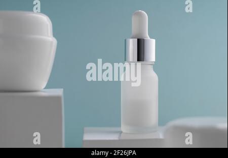 Pipet bottle and cream container on blue background Stock Photo