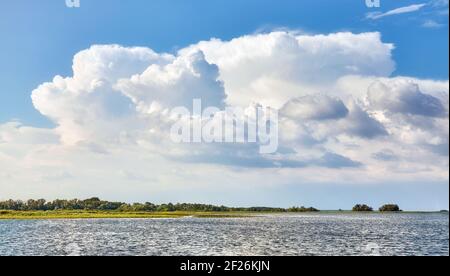 Scenic cloudscape over land and water on a sunny day. Stock Photo