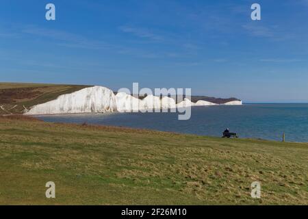 SEAFORD, SUSSEX/UK - APRIL 5 : Man Sitting on a Bench overlooking the Seven Sisters near Seaford in Sussex on April 5, 2018. Uni Stock Photo