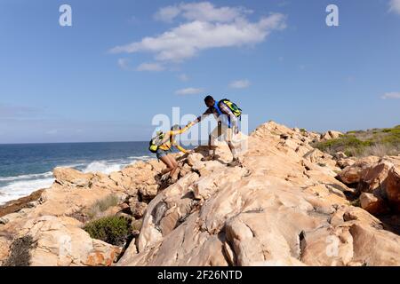 Fit afrcan american couple wearing backpacks hiking on the coast Stock Photo