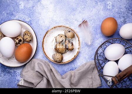 Quail and chicken eggs on blue background Stock Photo