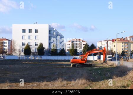 Orange Digger Parked Within apartments Stock Photo