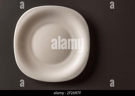 Close up view of white  square shaped plate on black background. Black and white background. Eating concept background. Stock Photo