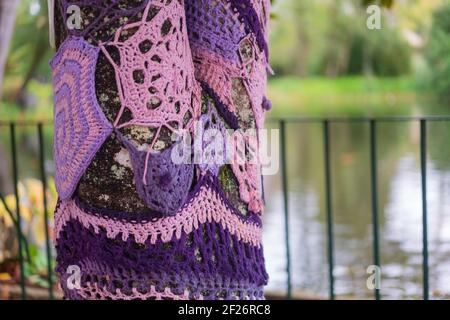 Colorful crochet knit on a tree trunk yarn bombing. Patchwork