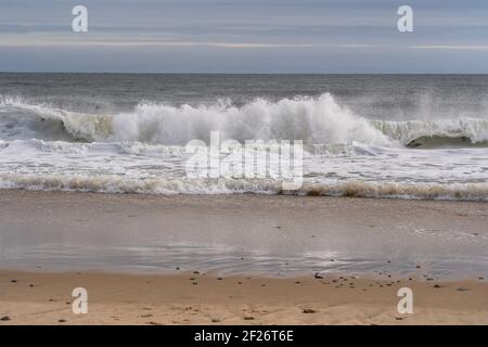 Waves crashing into the sand from a beach in Montauk at sunset Stock Photo
