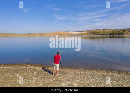 Drone shot of a caucasian man photographing a Landscape with a lake and reflection in Alentejo, Port Stock Photo