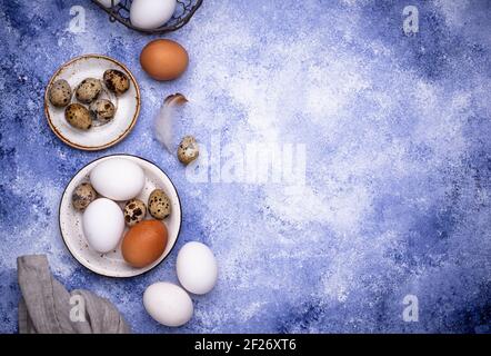 Quail and chicken eggs on blue background Stock Photo