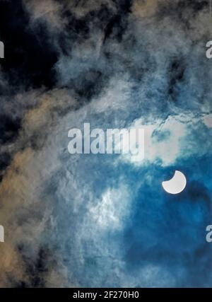 Partial eclipse of the sun viewed through clouds Stock Photo
