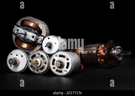 Small electric motors for driving domestic appliances. Electric devices stacked on a table. Dark background. Stock Photo