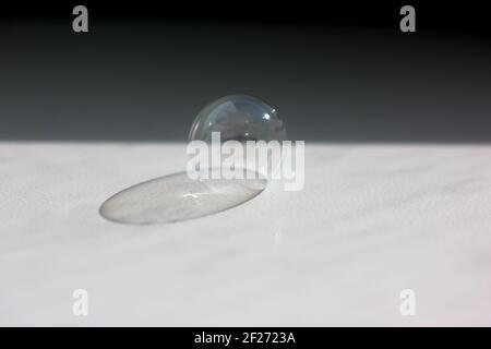 A huge soap bubble on a table and the shadow of a transparent soap ball. A contrasting black shadow separating the white surface into black and white. Stock Photo