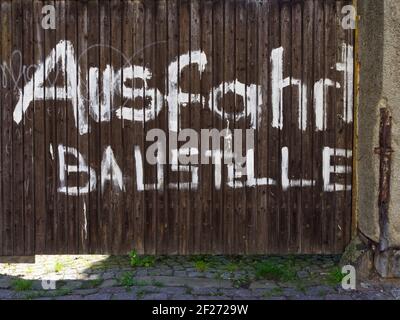 Large gate with German inscription 'Exit construction site'. Wooden door with large font. Tor mit weißer deutscher Aufschrift 'Ausfahrt Baustelle'. Stock Photo