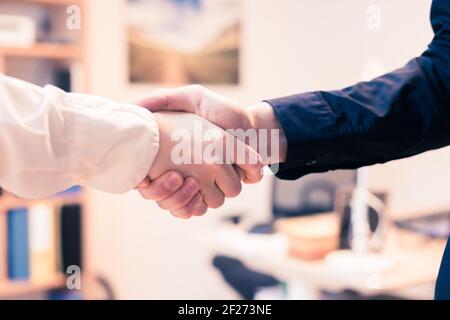Shaking hands, concept for teamwork: Close up of man and woman shaking hands in the office Stock Photo