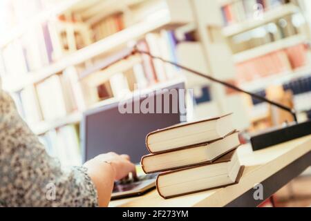 Learning for exams: Blonde female student in the university library, pile of books Stock Photo