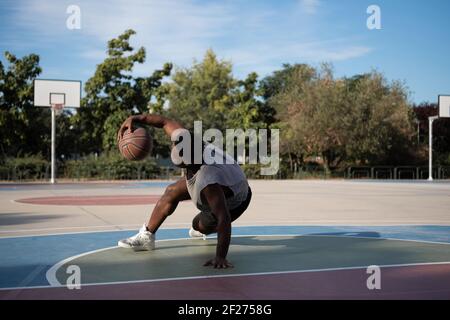 Muscular African American player doing freestyle dribbling on court Stock Photo