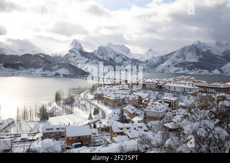 snowy town over full reservoir in Picos de Europa National Park Stock Photo