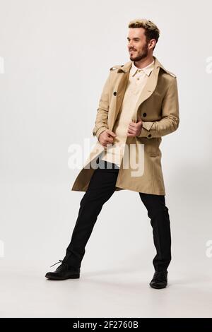 fashionable man in a beige coat trousers on a light background fashion trend of the season spring Stock Photo