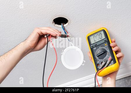 Electrician hands check with tester power supply before installing