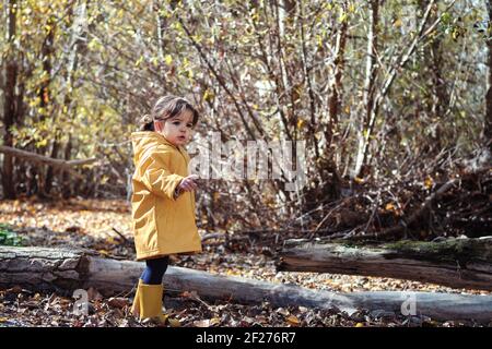 A 2 year old girl in a yellow raincoat in nature Stock Photo