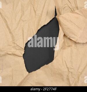 Brown sheet of paper with a torn hole and a curled strip Stock Photo