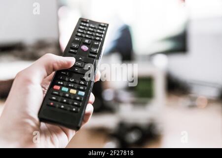 Male hand is holding TV remote control, smart TV. Stock Photo