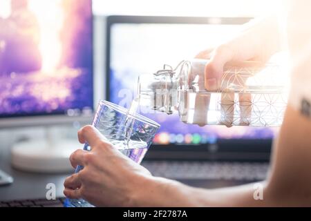 Drinking water in the office: close up of glass bottle, workplace Stock Photo