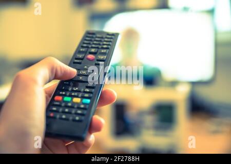 Male hand is holding TV remote control, smart TV. Stock Photo