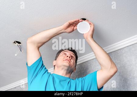 electrician installing LED spotlights on the ceiling Stock Photo