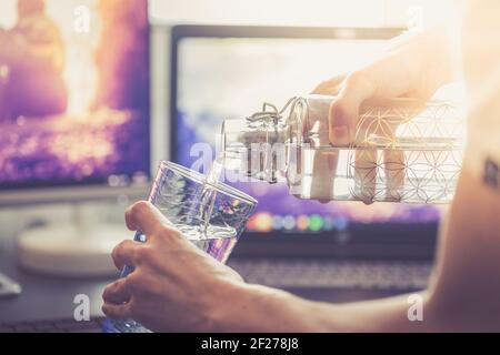 Drinking water in the office: close up of glass bottle, workplace Stock Photo