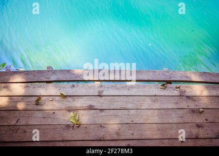 Wooden dock pier extending over blue lake, copy space Stock Photo