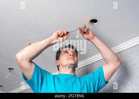 An electrician is installing an LED spotlight in the ceiling Stock ...